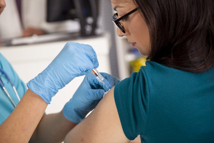 Medical: Nurse at pharmacy clinic giving flu shot to patient. Flu season! Nurse at pharmacy or clinic giving flu shot to a female patient. Syringe, needle.