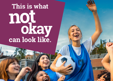 Young soccer player is celebrated by her team for scoring a goal, with the text "This is what not okay can look like."